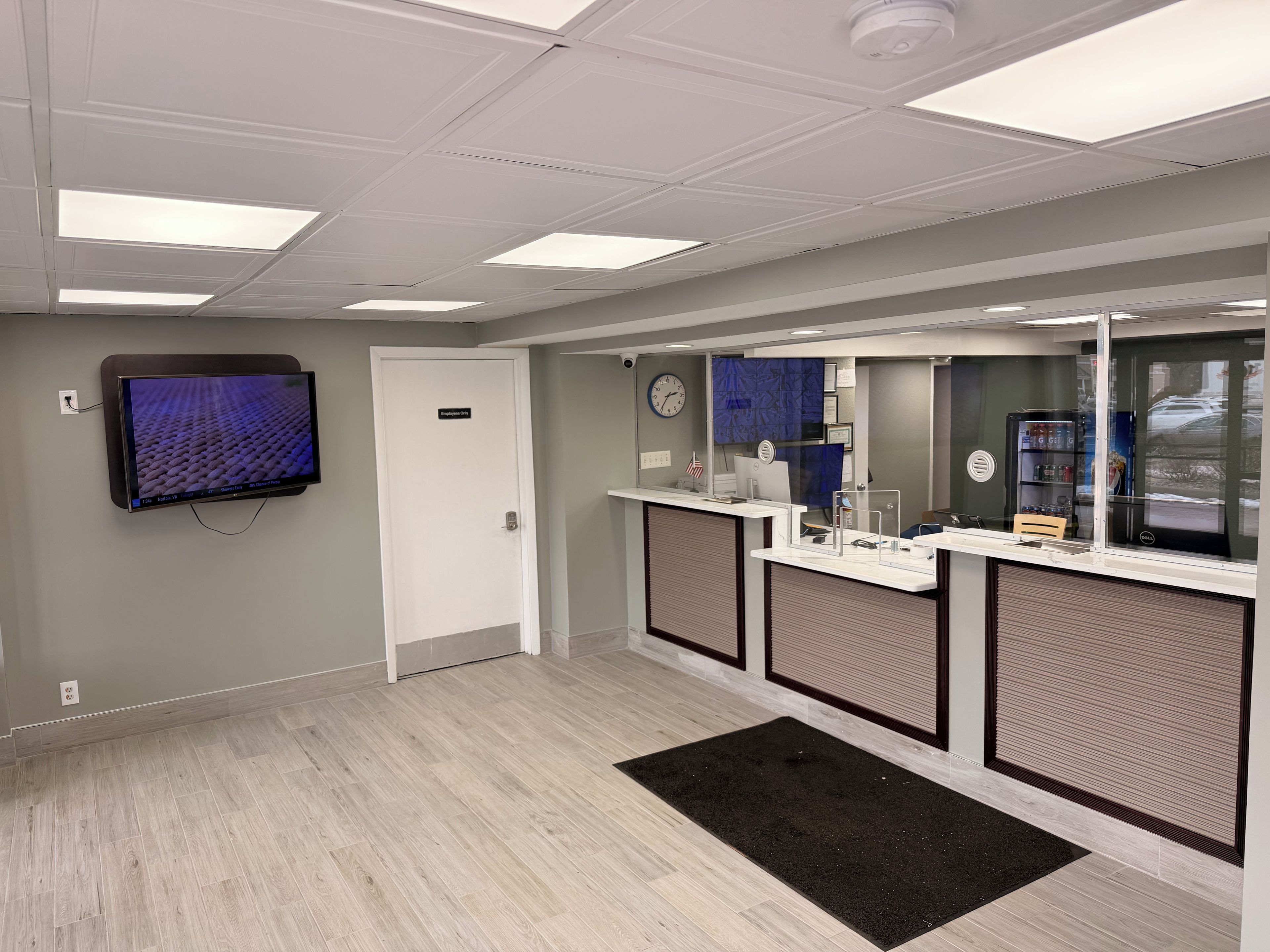 A reception area with a reception desk, a computer, a clock, and a television mounted on the wall.