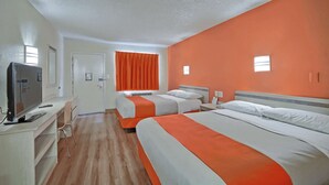 Une chambre d’hôtel avec deux lits, une télévision, un bureau et une fenêtre avec des rideaux orange.