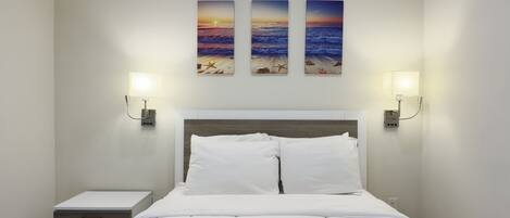A hotel room with a bed, bedside tables, and wall-mounted artwork.