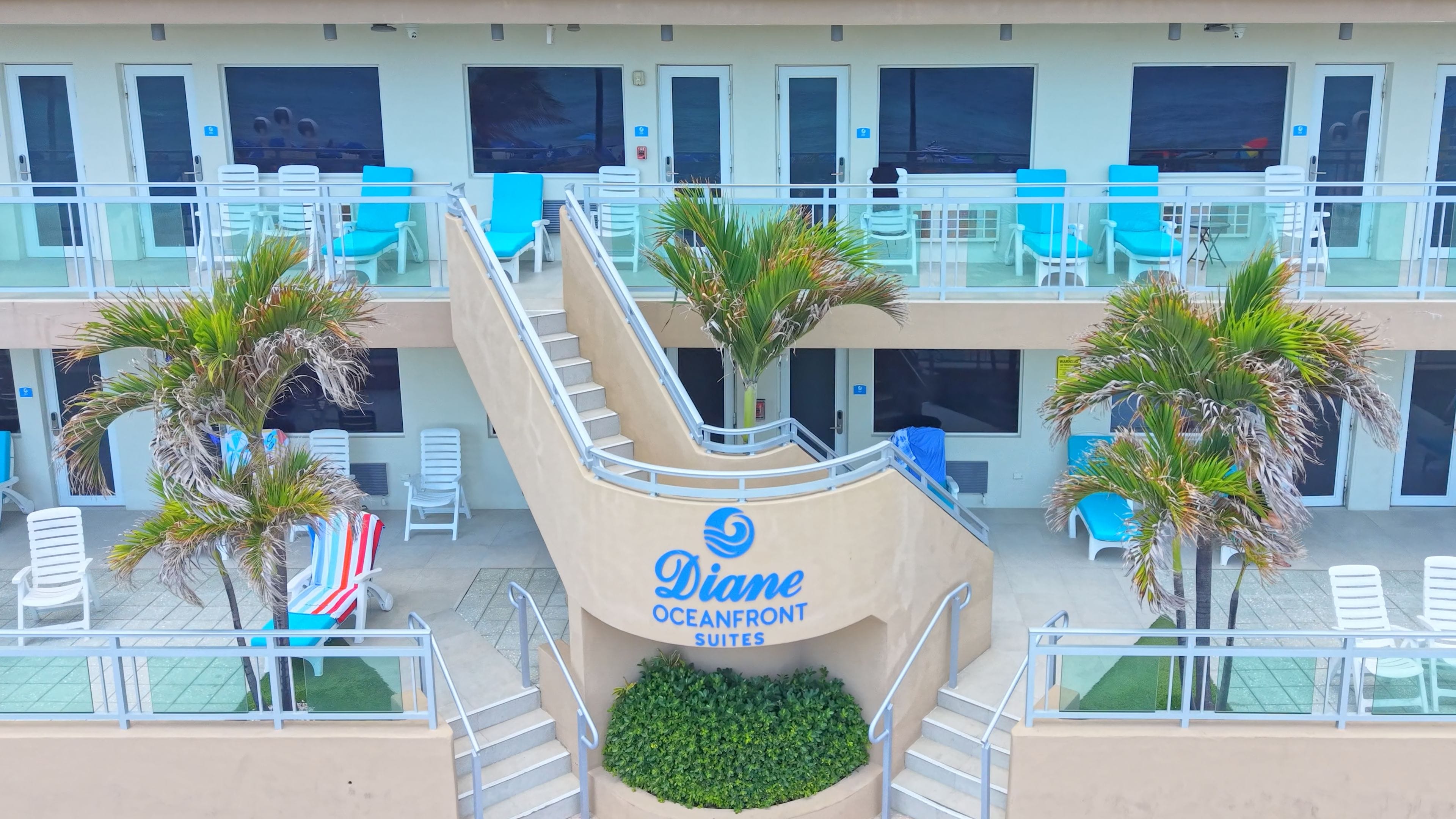 A hotel with multiple balconies, outdoor seating, and palm trees.
