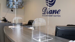 Una sala de conferencias con un divisor de vidrio, una computadora Lenovo y una pantalla fija mostrando varias imágenes.