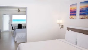 Una habitación de hotel con una cama grande, un escritorio y vista a la playa.