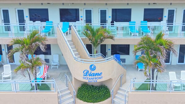 Un hotel con varios balcones, mobiliario exterior y palmeras.