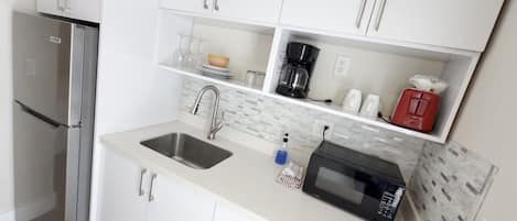 A modern kitchen with a stainless steel refrigerator, a double sink, and a microwave.