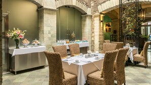 Un restaurante con sillas de mimbre, un bufé y un arco de ladrillo.