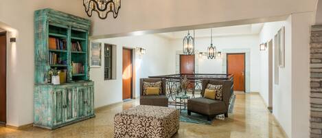 A spacious living area with a large teal cabinet, a patterned ottoman, and a dining set.