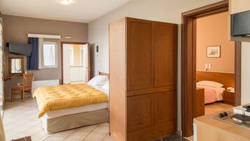 A bedroom with a bed, wooden wardrobe, a desk with a chair, and a television.