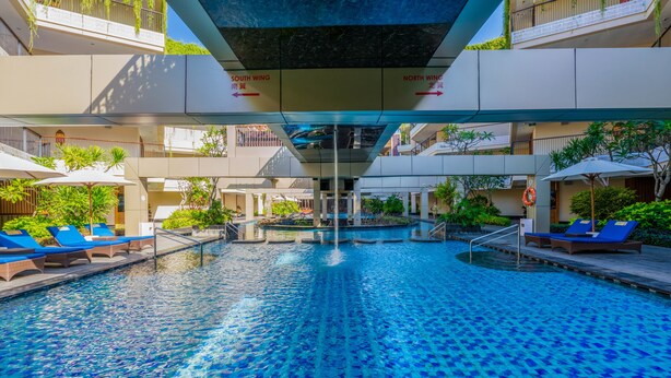 A swimming pool with blue tiles, lounge chairs, and a waterfall feature.