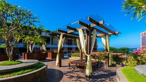 An outdoor patio area with a wooden pergola, seating, and planters.