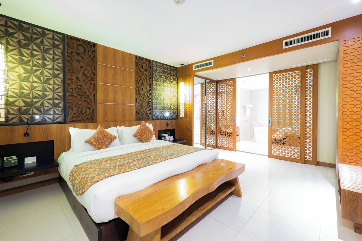 A modern bedroom with a large bed, wooden headboard, and a bench.