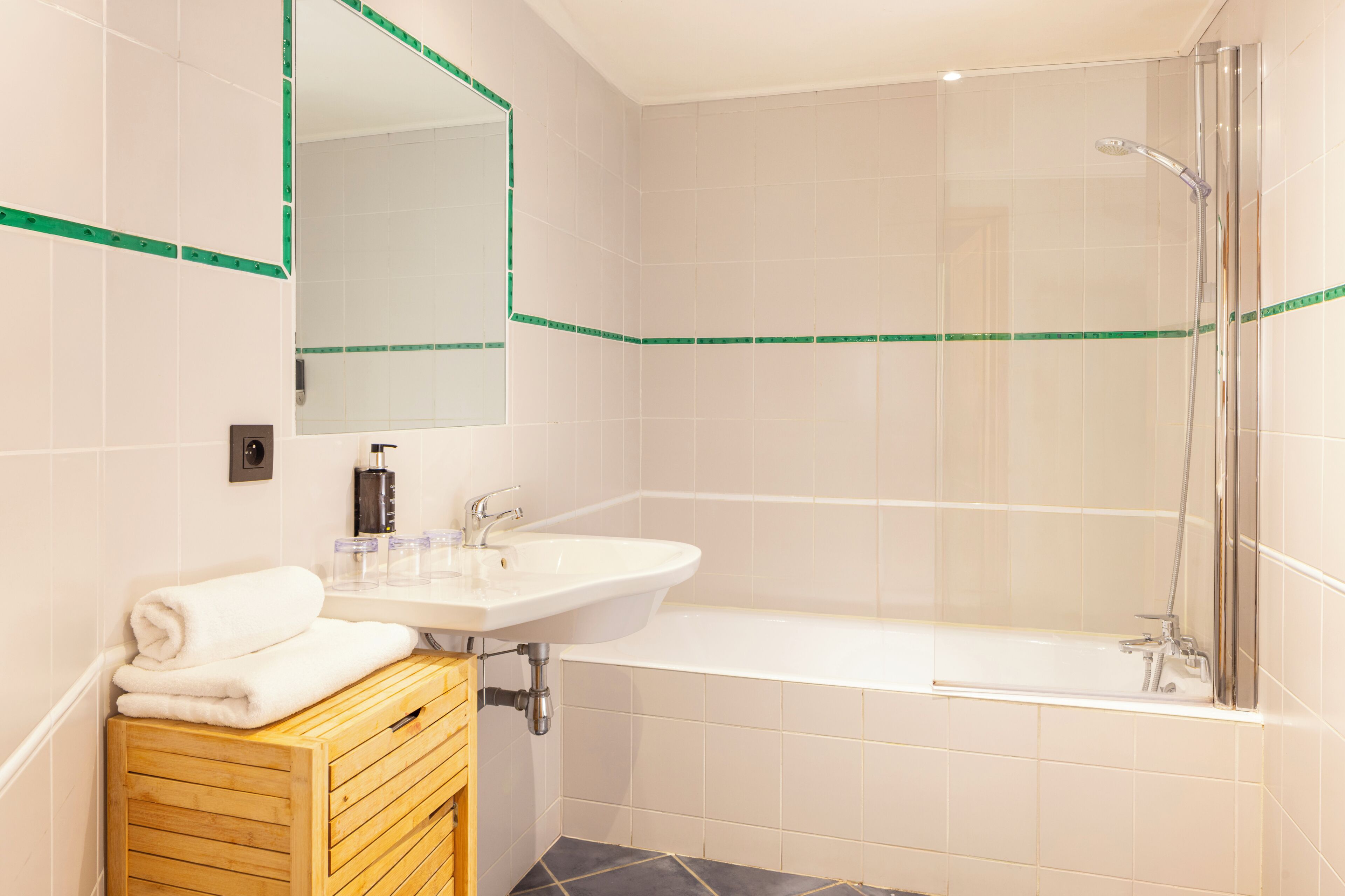 A bathroom with a sink, mirror, and shower.