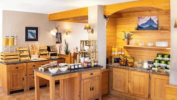 A wooden kitchen with a central island, wooden cabinets, and various food items displayed.