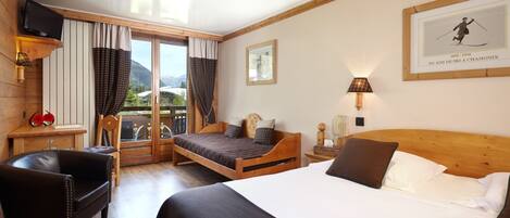 Une chambre d’hôtel avec un lit en bois, un fauteuil en cuir, un bureau avec une lampe et une fenêtre avec des rideaux.