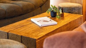 Una habitación acogedora con una pared de madera, un sofá, una mesita de café con un libro y una planta, y una lámpara.