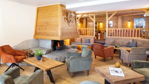 Una zona de estar acogedora con chimenea de piedra, vigas de madera y asientos cómodos.