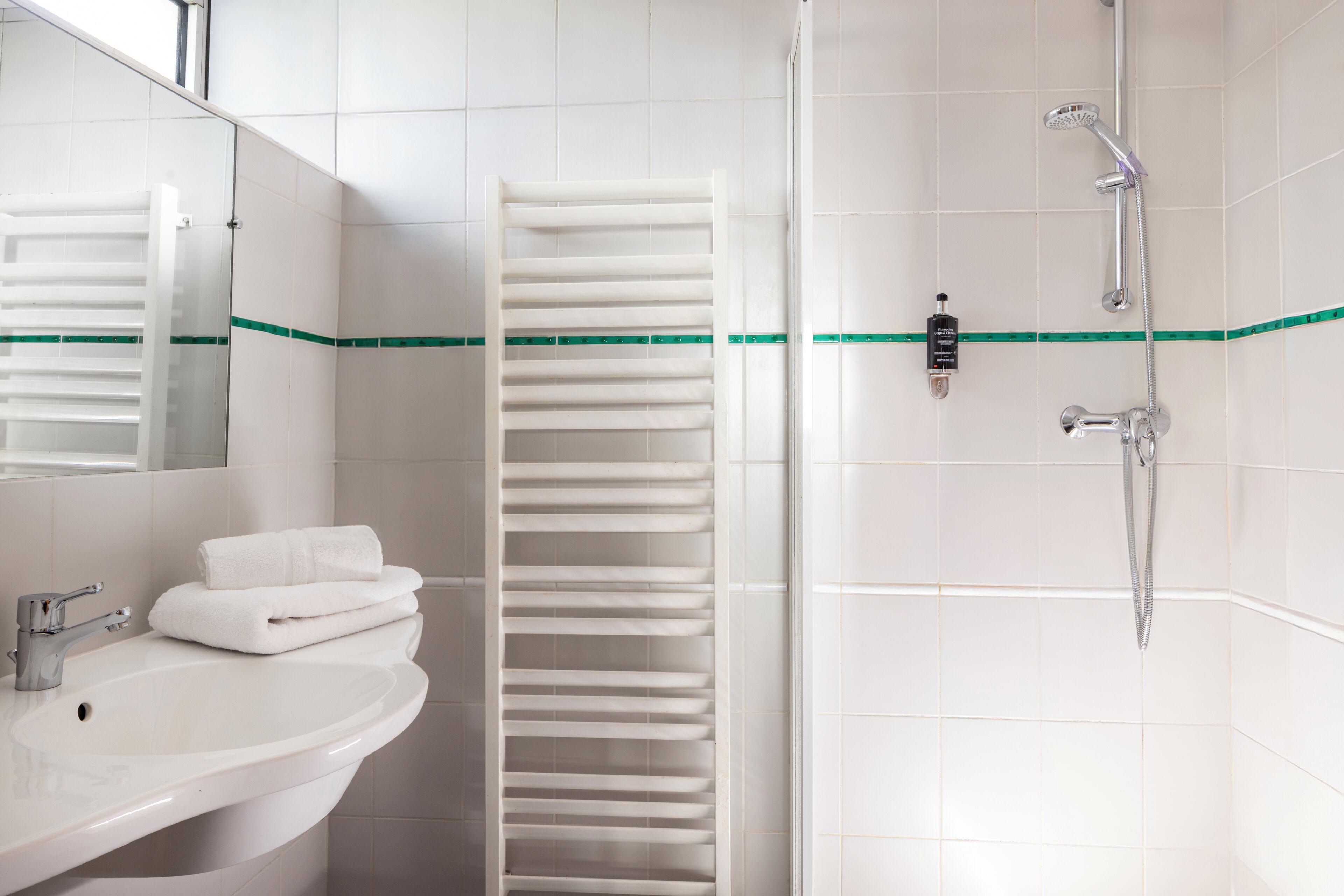 A bathroom with a sink, mirror, towel rack, and shower.