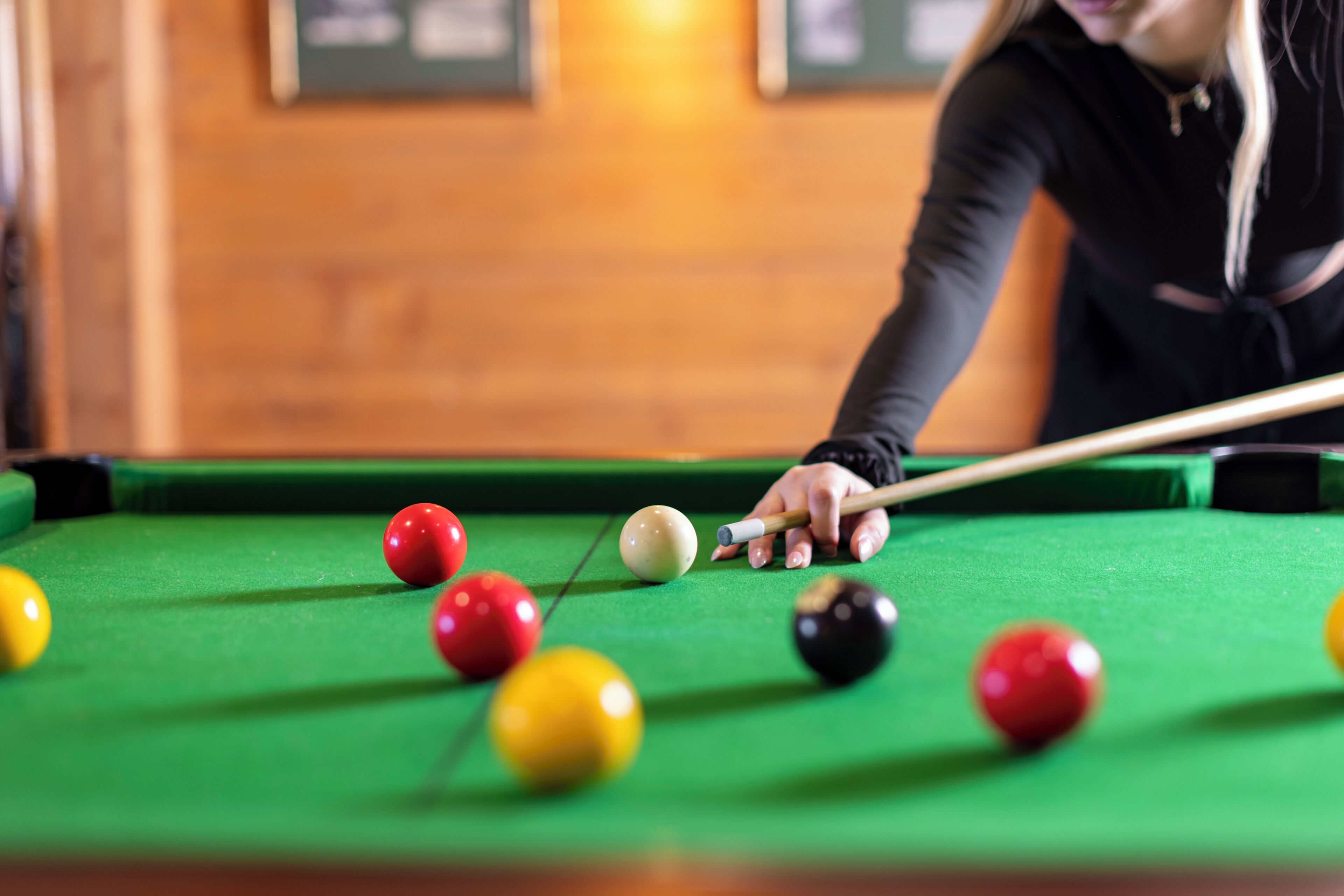A pool table with balls and a cue stick.