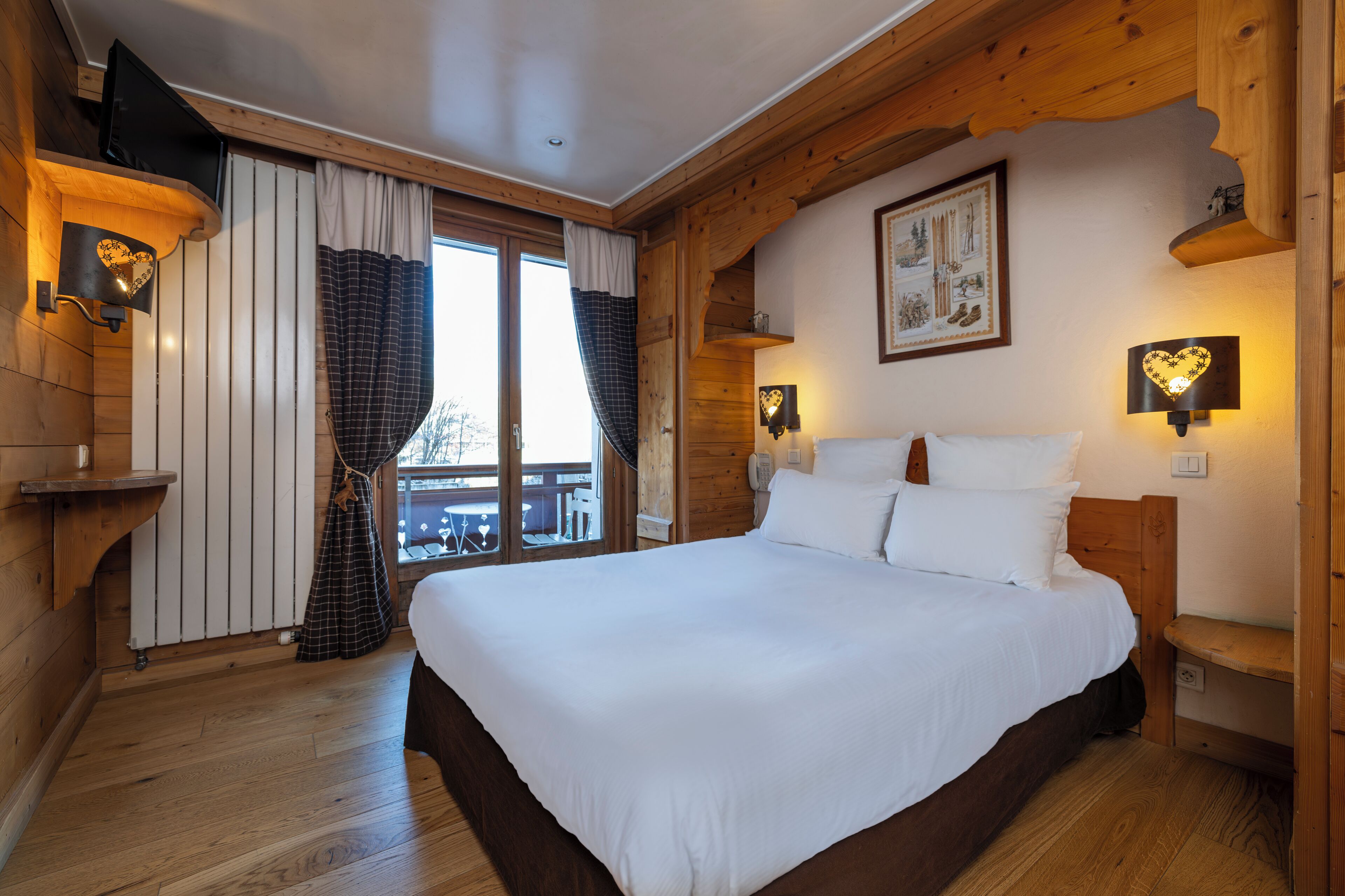 Un dormitorio de cabaña de madera con una cama grande, paredes de madera y una ventana con cortinas.