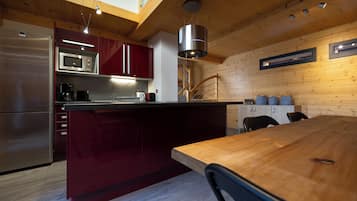 Una cocina moderna con techo de madera, una isla central y electrodomésticos integrados.