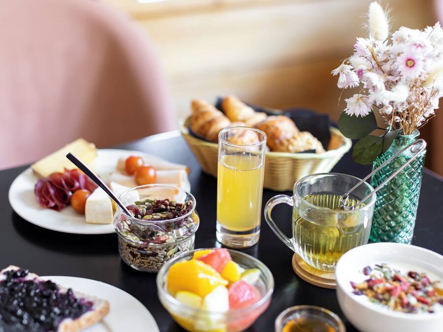 A breakfast table with various food items, including fruits, pastries, and beverages.