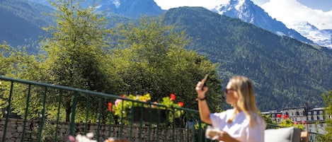 A person sitting on a bench with a mountainous landscape in the background.