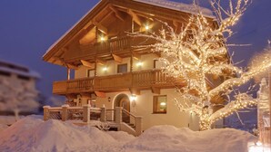 Un edificio cubierto de nieve con fachada de madera, balcones y una escalera que lleva a la entrada.