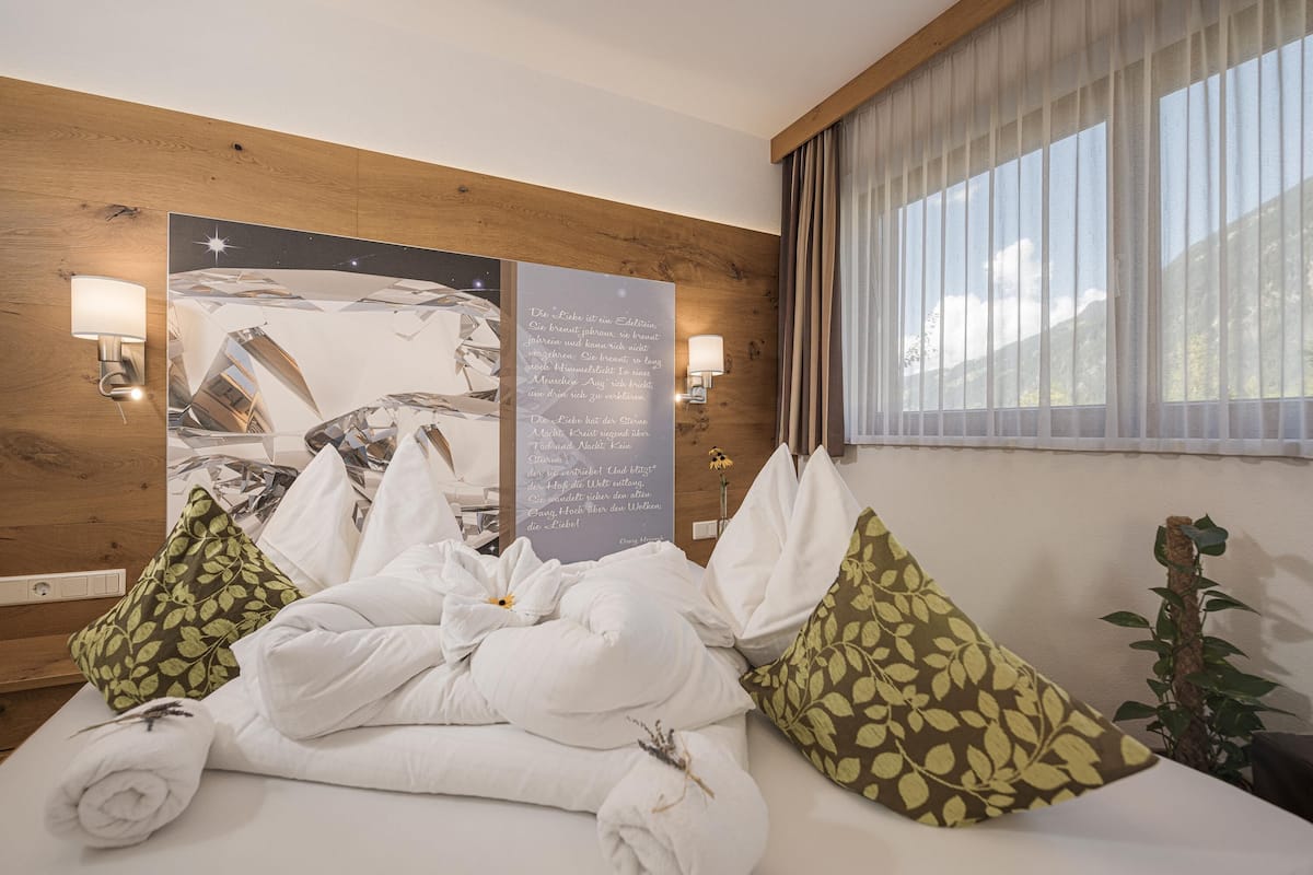 Une chambre d’hôtel avec un mur en bois, une grande affiche, deux lampes murales et une fenêtre avec des rideaux.