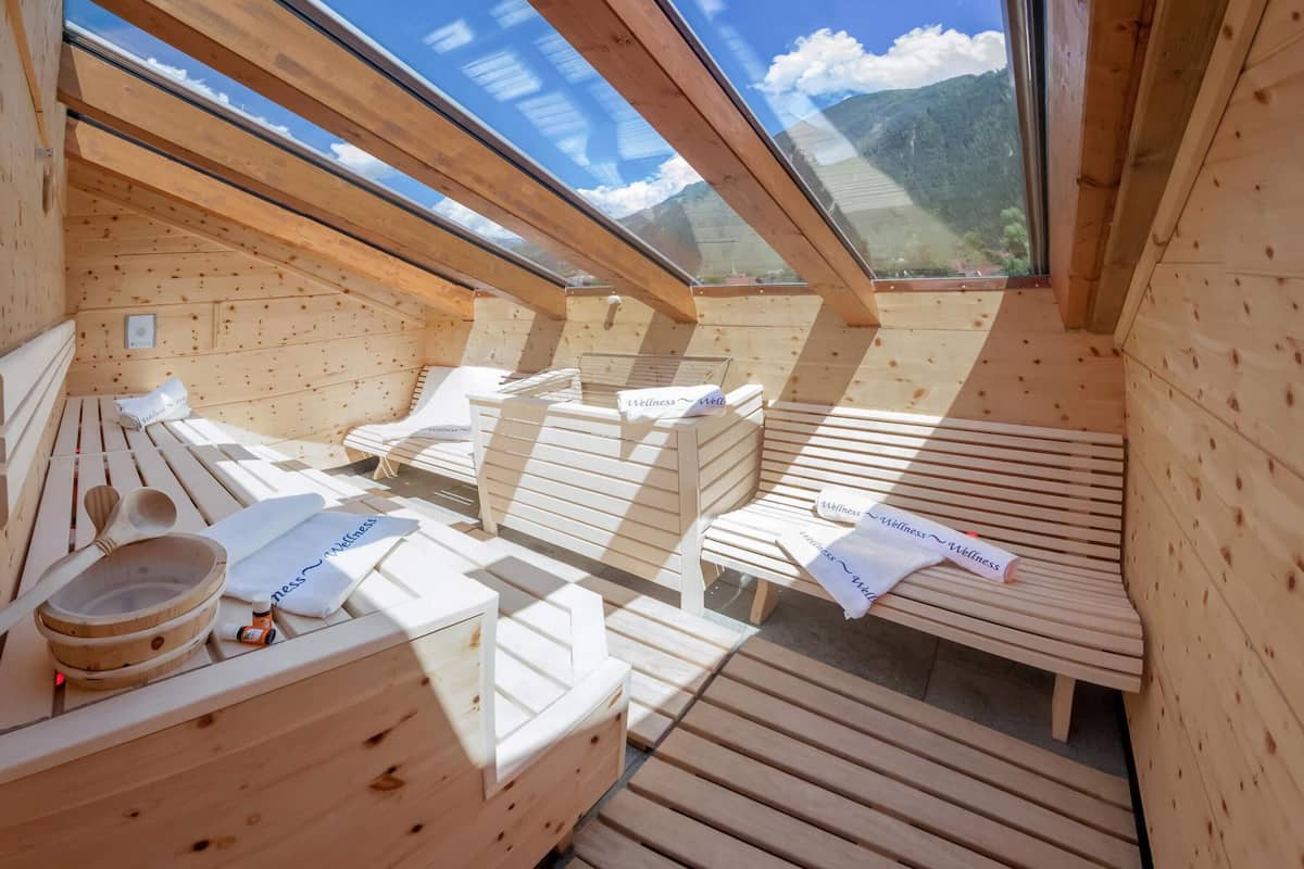Un sauna en bois, avec des bancs et une table en bois sur laquelle sont posées des serviettes et une cuillère en bois.