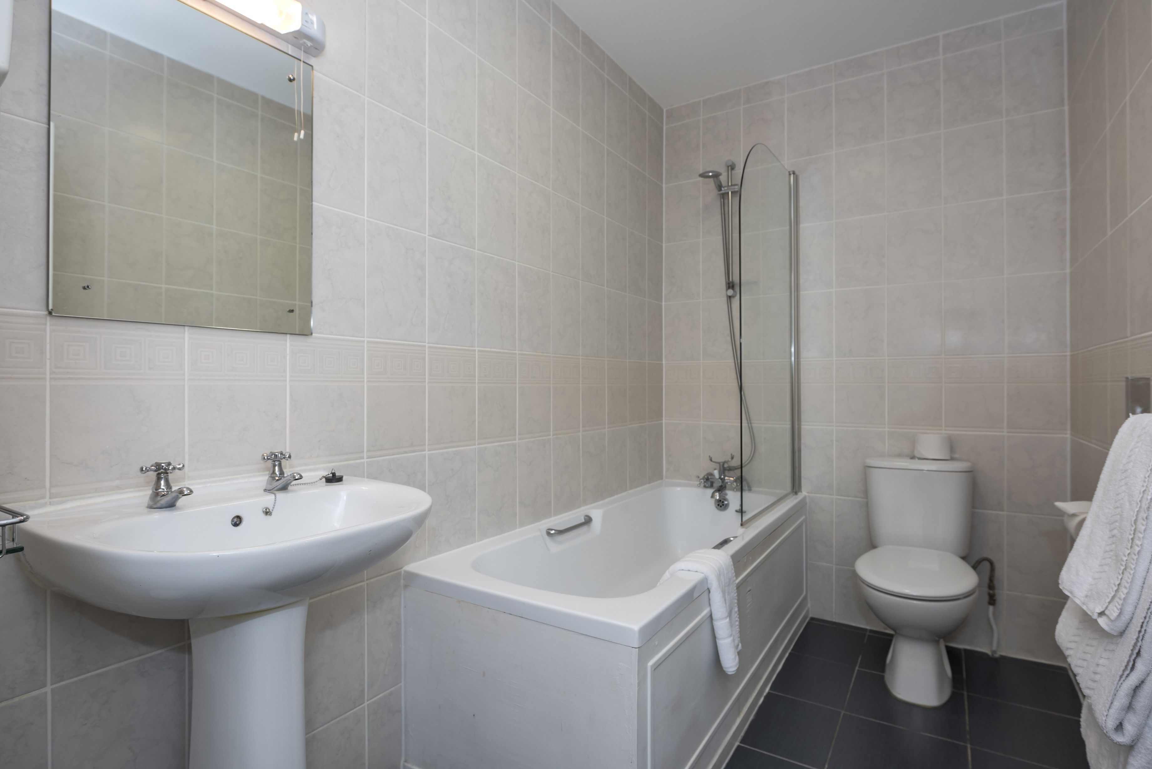 A bathroom with a sink, bathtub, toilet, and a mirror.