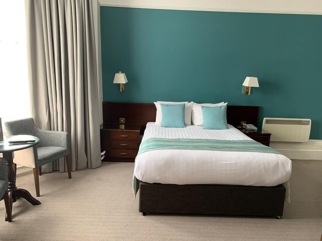 A hotel room with a large bed, two bedside tables, a chair, and a desk.