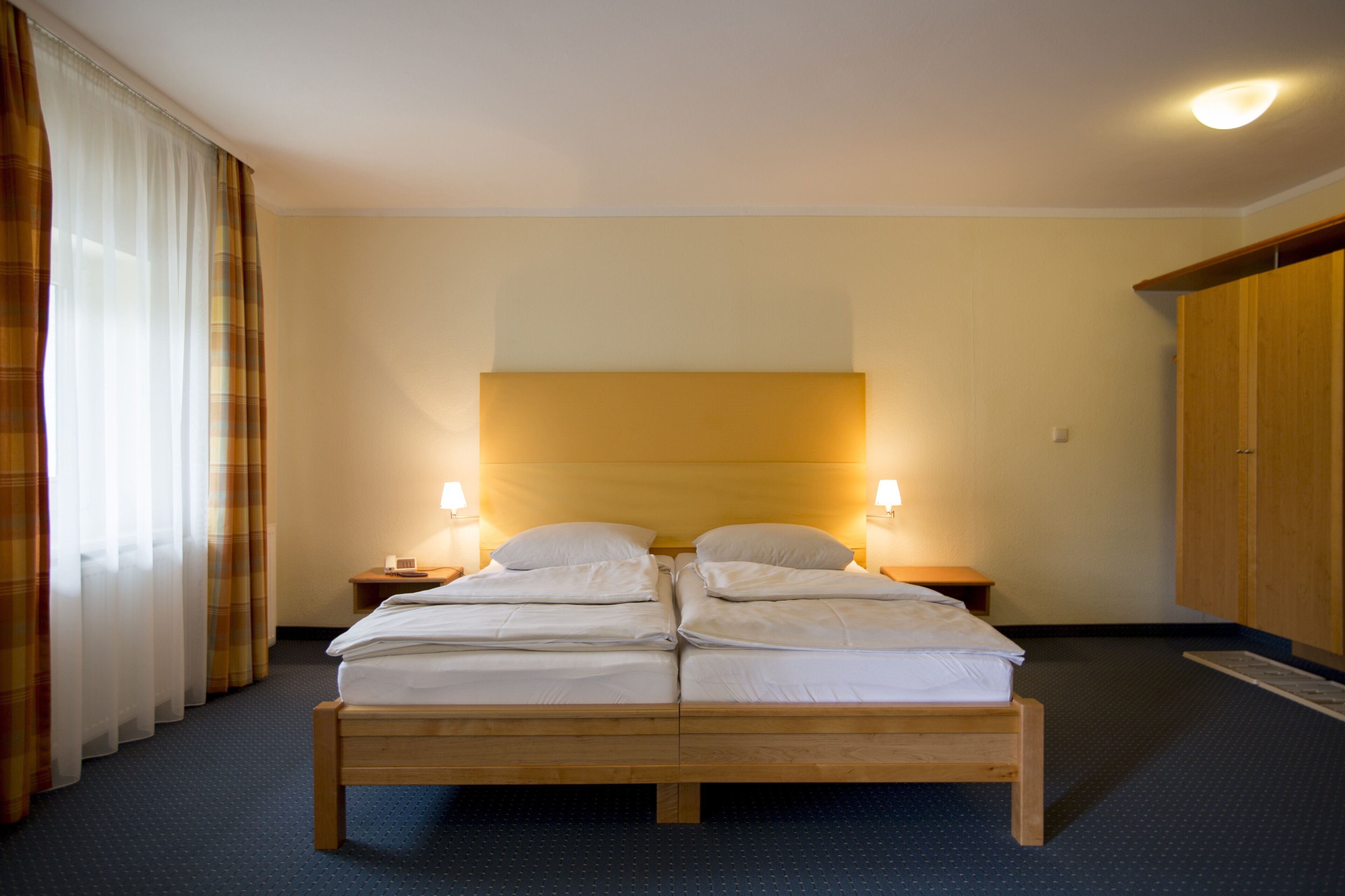 A double bed with a wooden frame, two bedside tables with lamps, and a wardrobe.