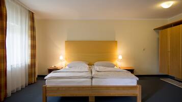 A double bed with a wooden frame, two bedside tables with lamps, and a wardrobe.