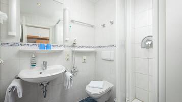 Un baño con lavamanos, inodoro y ducha.