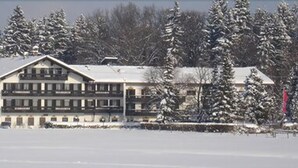 Un edificio de varios pisos con techo plano, rodeado de árboles cubiertos de nieve.