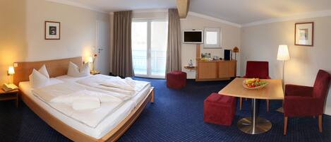 A hotel room with a large bed, a desk, a chair, and a TV.