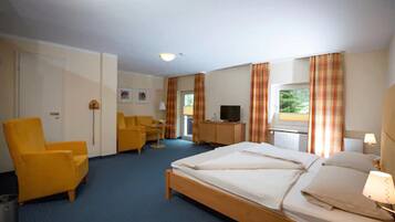 A hotel room with a bed, a desk, a chair, and a television.