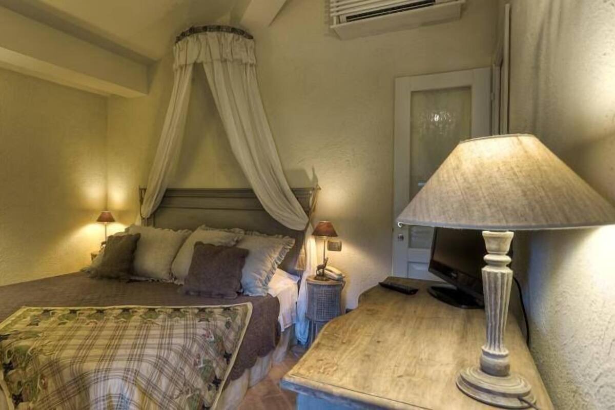 Een slaapkamer met een bed, een nachtkastje met een lamp, en een hemelbed.