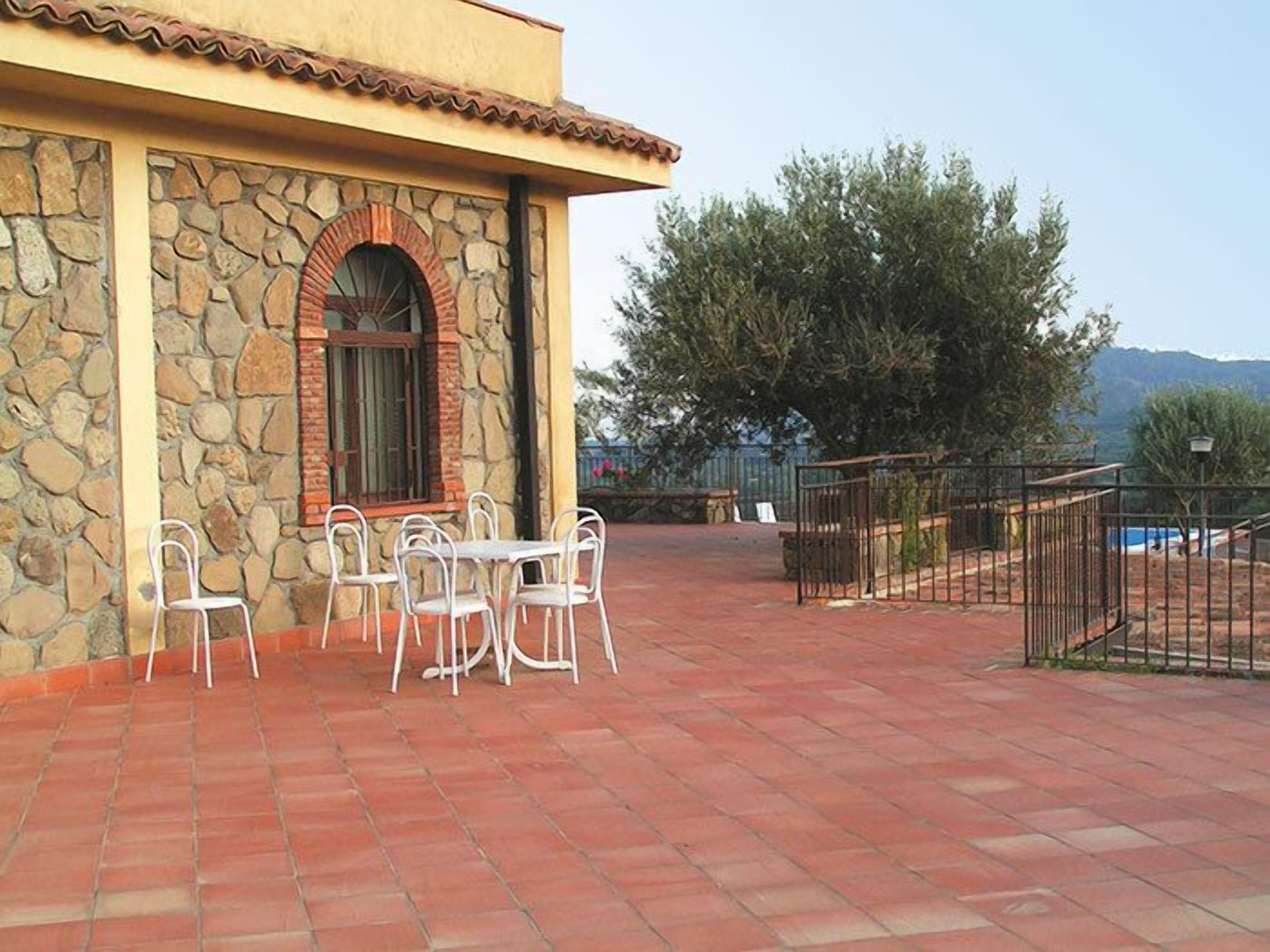 Un patio con paredes de piedra, suelo de ladrillo y mobiliario exterior.