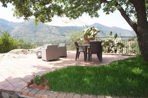 Une terrasse avec des meubles d’extérieur, un cactus et une vue sur les montagnes.