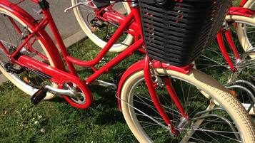A red bicycle with a basket attached to the front, parked on grass.