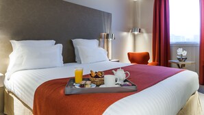 Une chambre d’hôtel avec un grand lit, un plateau avec des articles pour le petit-déjeuner, une fenêtre avec des rideaux et une petite table avec une lampe.