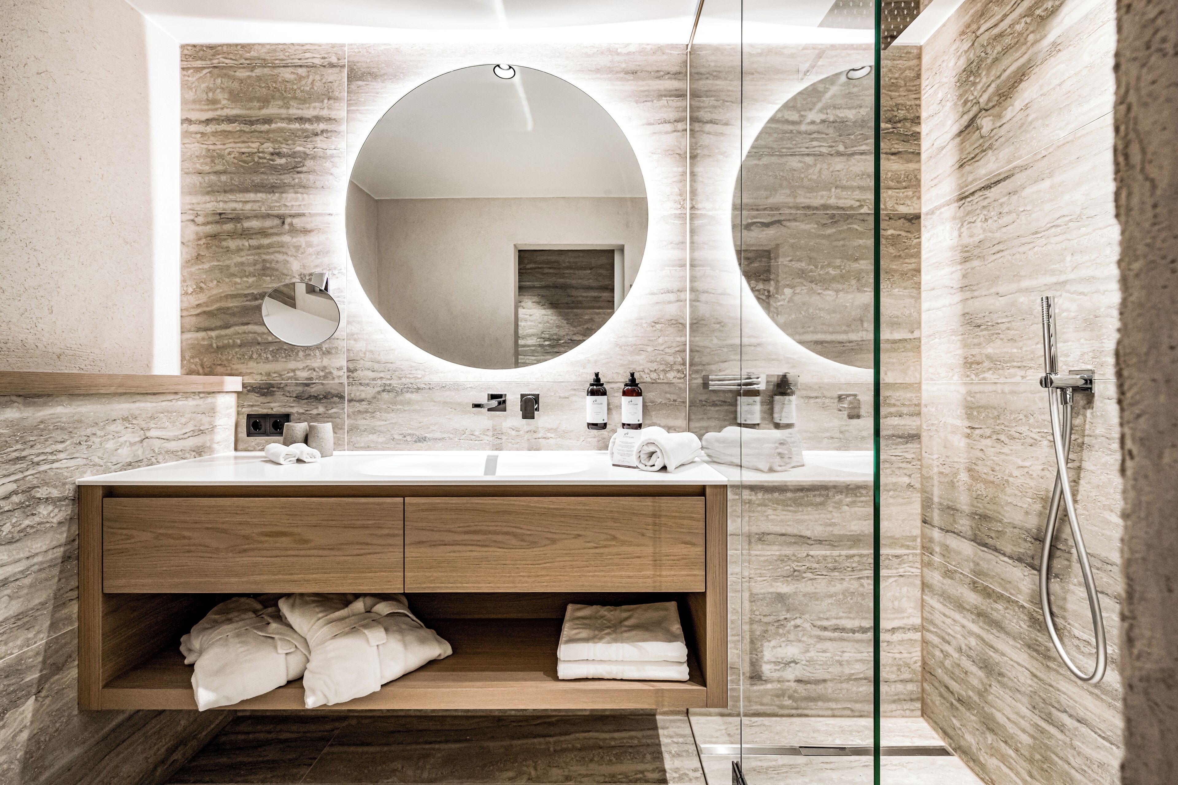 Une salle de bain moderne avec un grand miroir, un meuble-lavabo en bois et une cabine de douche en verre.