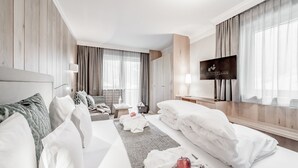 Habitación de hotel con una cama grande, un sofá, un televisor y una ventana con cortinas.