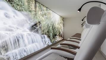Experience ultimate relaxation in our serene spa area, featuring massage chairs and a stunning mural of a waterfall and lush greenery.