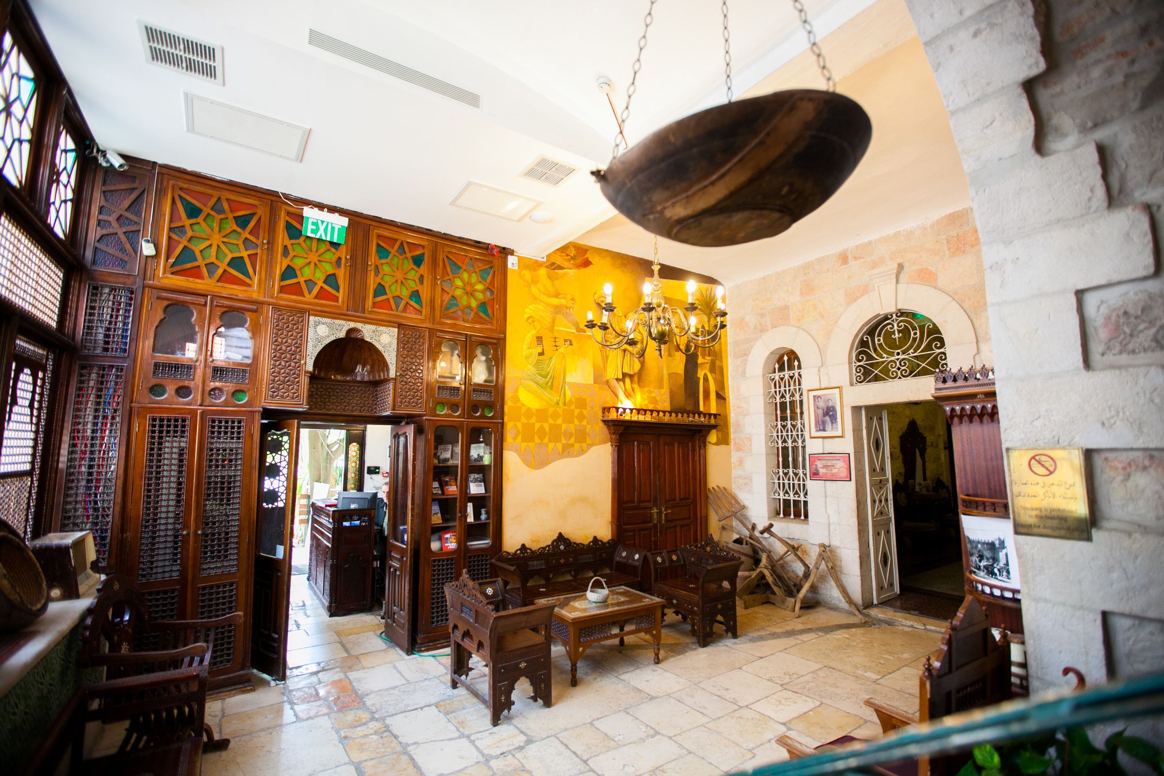 A traditional interior with wooden furniture, a chandelier, and an exit sign.