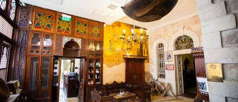 A traditional interior with wooden furniture, a chandelier, and an exit sign.