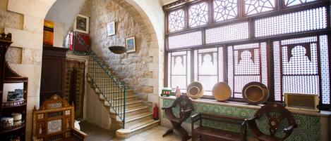 A historic interior with a stone archway, a staircase, and traditional furniture.