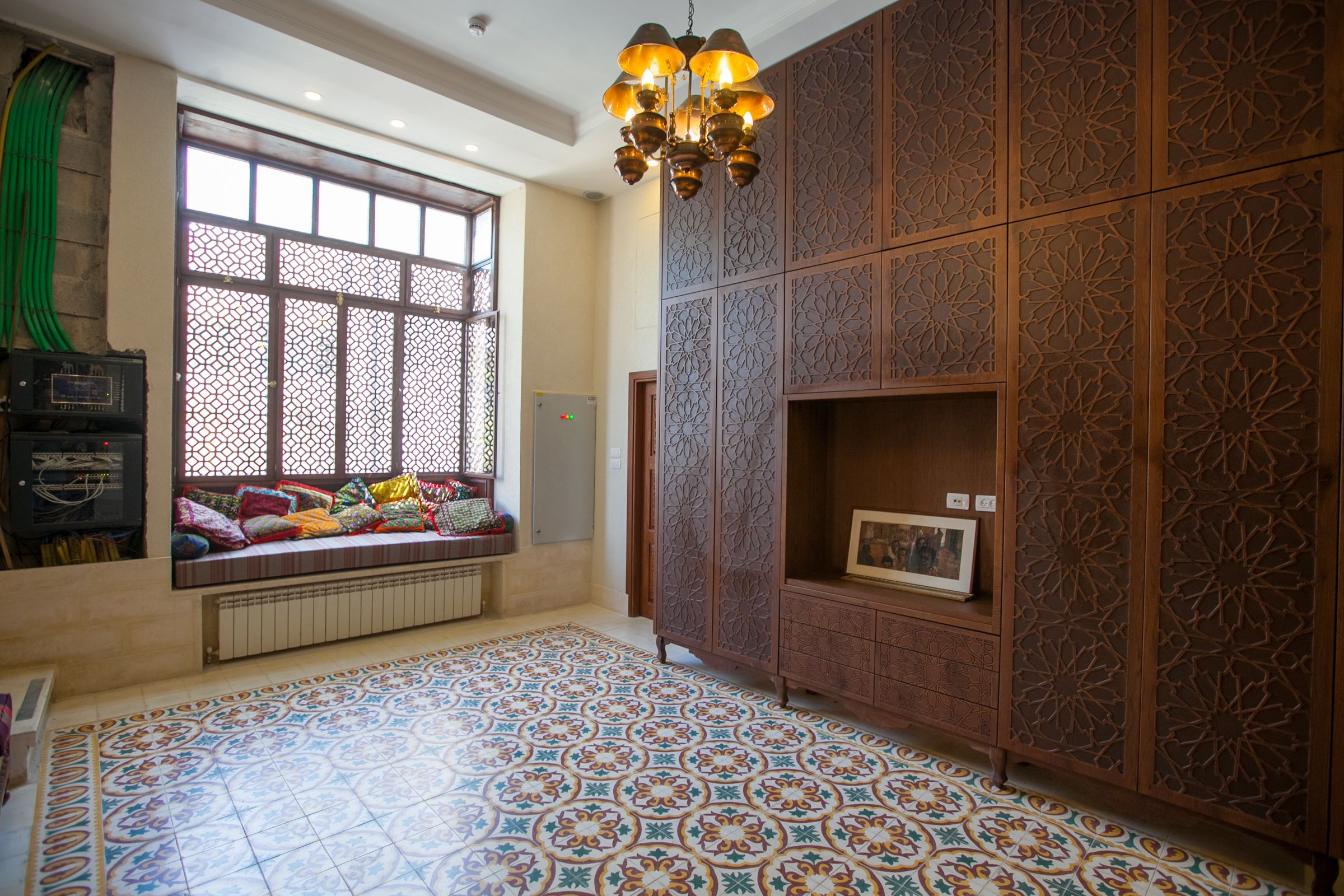 Una habitación con piso estampado, una ventana con asiento y un mueble decorativo.