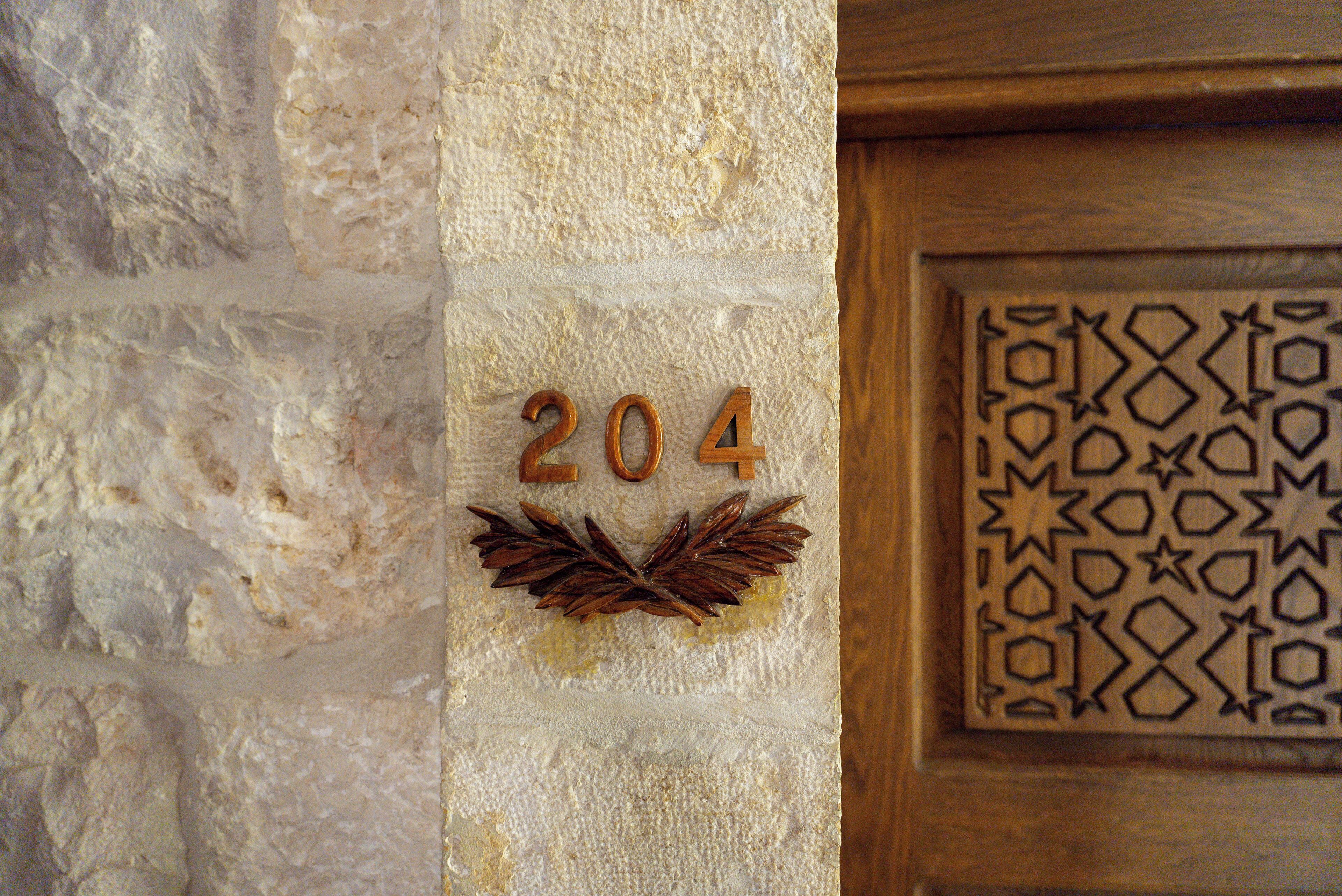 Eine strukturierte Wand mit der Nummer '204' und einem dekorativen Lorbeerkranz.