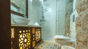 A modern bathroom with a large sink, a glass shower enclosure, and a patterned floor.